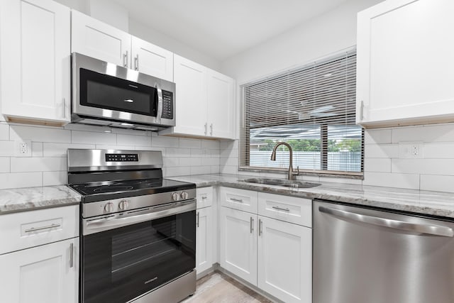 kitchen featuring white cabinets, a sink, tasteful backsplash, and appliances with stainless steel finishes