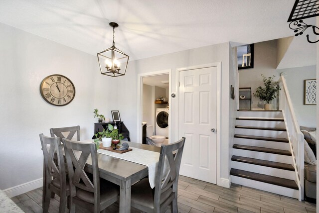 dining space with stairs, wood finish floors, a chandelier, and washer / dryer