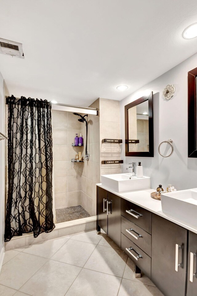 full bathroom with visible vents, a shower stall, double vanity, a sink, and tile patterned flooring