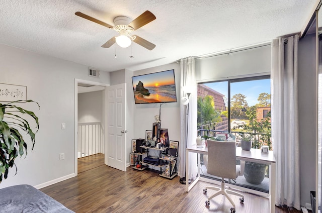 home office with wood finished floors, a textured ceiling, baseboards, visible vents, and ceiling fan