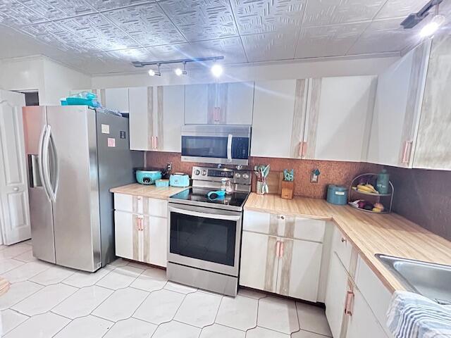 5372 Pine Cir, Coral Springs, FL 33067 - kitchen with stainless steel appliances, light countertops, white cabinetry, an ornate ceiling, and backsplash