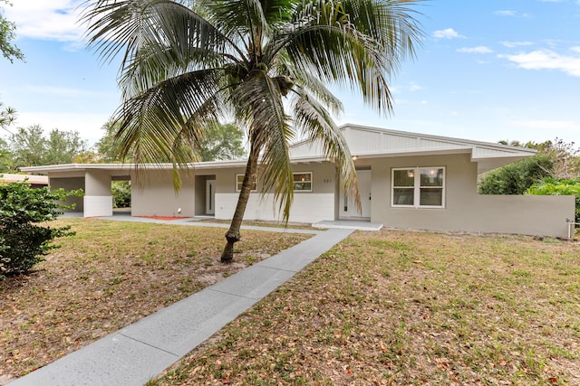 view of front of property with stucco siding, a front lawn, a porch, and a carport