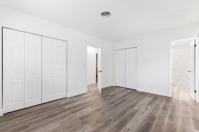 unfurnished bedroom with baseboards, visible vents, and wood finished floors