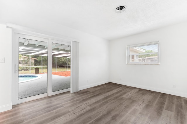 spare room featuring baseboards, visible vents, and wood finished floors