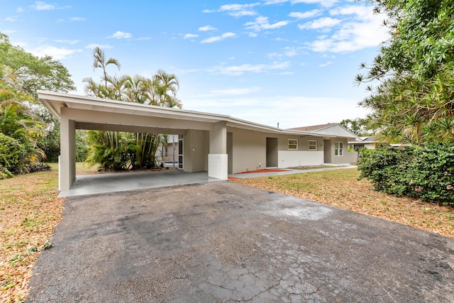 view of front of property with driveway, an attached carport, and stucco siding