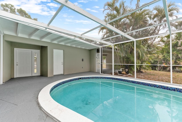 pool featuring glass enclosure and a patio area