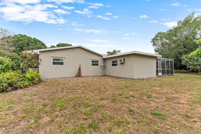 rear view of house with stucco siding and a yard