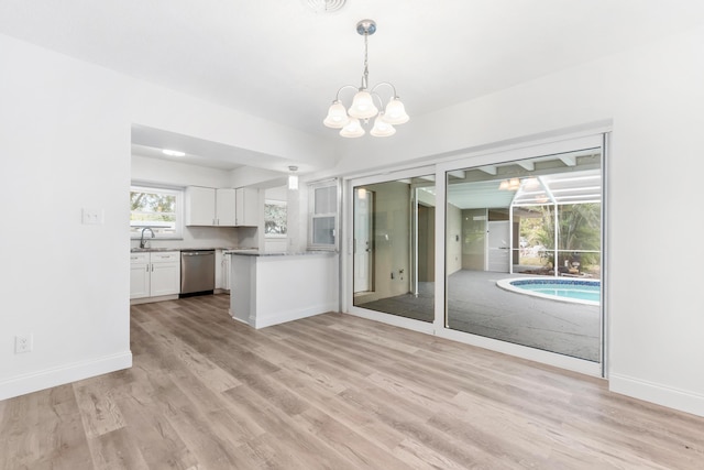 kitchen with white cabinetry, a sink, light wood-style floors, dishwasher, and a notable chandelier