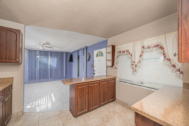 2008 Avenue Ave N, Fort Pierce, FL 34950 - kitchen with a ceiling fan, light tile patterned flooring, a peninsula, and a textured ceiling