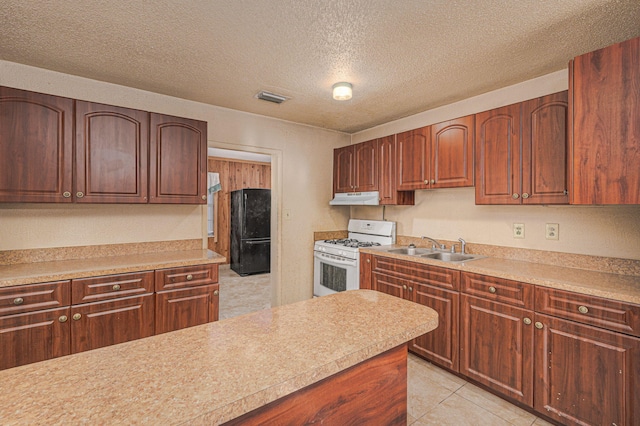 2008 Avenue Ave N, Fort Pierce, FL 34950 - kitchen with white gas stove, freestanding refrigerator, under cabinet range hood, visible vents, and a sink