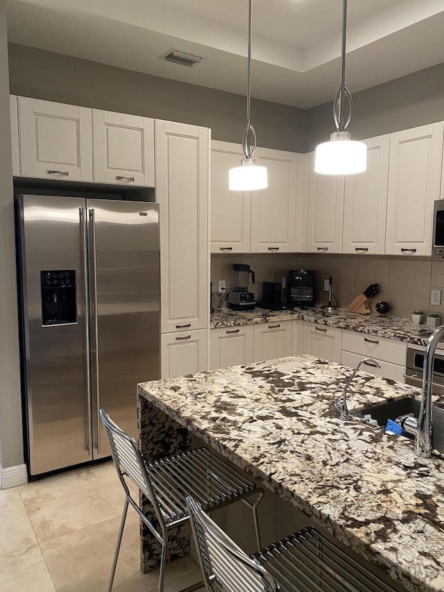 8481 NW 51st Ter, Doral, FL 33166 - kitchen with decorative backsplash, visible vents, stainless steel appliances, white cabinetry, and light stone counters