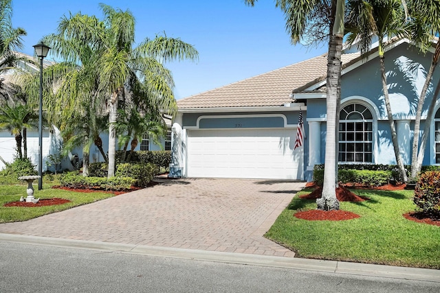 551 NW Red Pine Way, Jensen Beach, FL 34957 - view of front facade featuring a garage, a tiled roof, stucco siding, and driveway