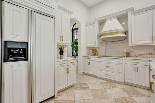 9387 Satinleaf Pl, Parkland, FL 33076 - kitchen featuring black electric cooktop, paneled built in refrigerator, white cabinetry, premium range hood, and arched walkways