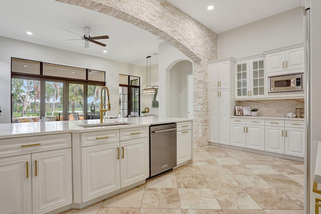 9387 Satinleaf Pl, Parkland, FL 33076 - kitchen featuring arched walkways, stainless steel appliances, light countertops, ceiling fan, and a sink