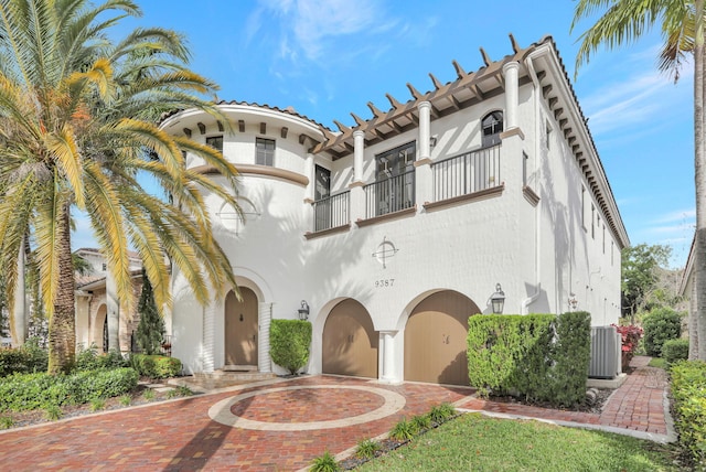 9387 Satinleaf Pl, Parkland, FL 33076 - exterior space featuring a balcony, central air condition unit, curved driveway, stucco siding, and a garage