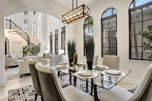 9387 Satinleaf Pl, Parkland, FL 33076 - tiled dining area with arched walkways, a chandelier, baseboards, stairway, and a towering ceiling