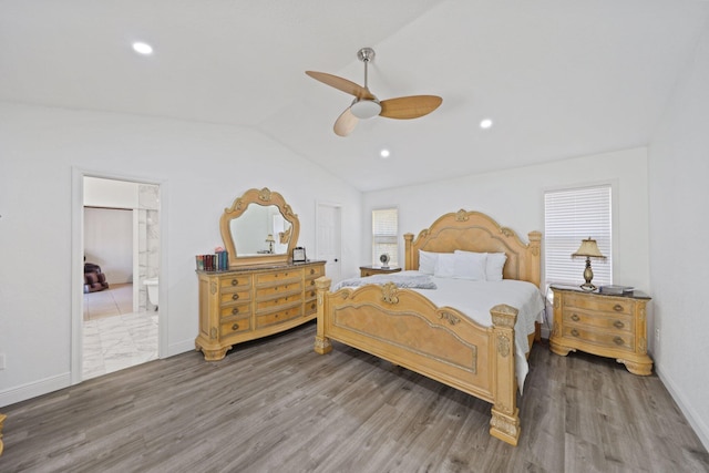 bedroom featuring wood finished floors, lofted ceiling, ensuite bath, baseboards, and recessed lighting