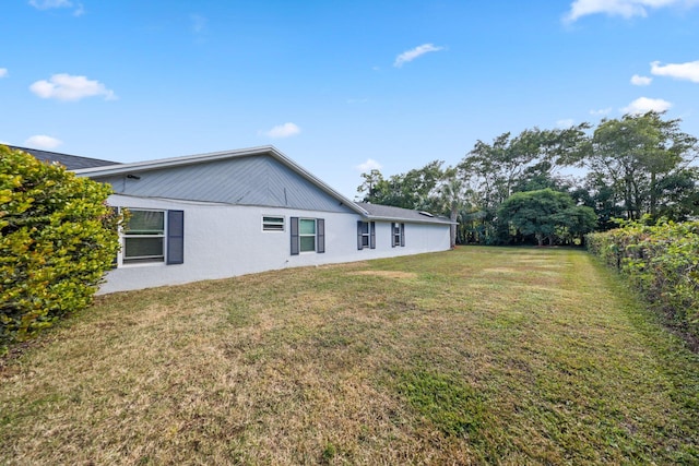 rear view of property with a lawn and stucco siding