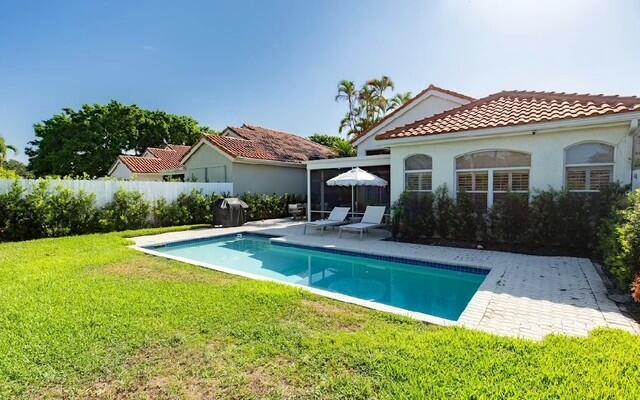 12624 Mallet Cir, Wellington, FL 33414 - back of house with a tile roof, a patio area, a fenced in pool, fence, and a lawn