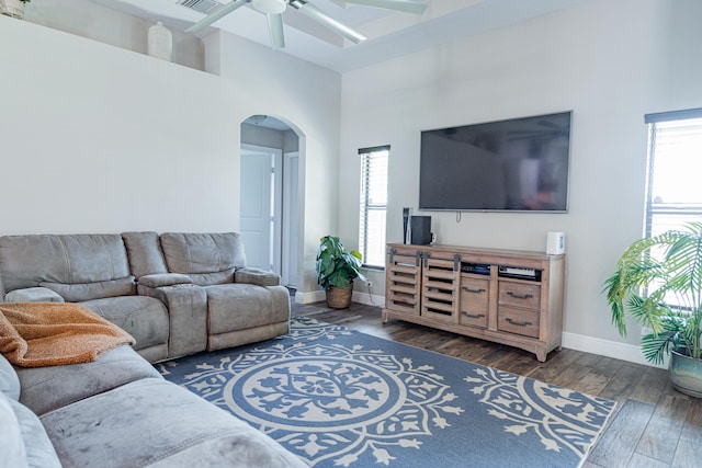 living room with a wealth of natural light, arched walkways, hardwood / wood-style floors, and a ceiling fan