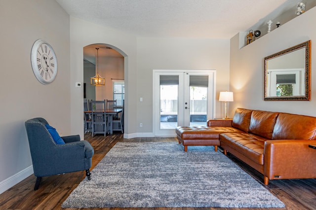 living room featuring baseboards, a chandelier, french doors, dark wood-type flooring, and arched walkways