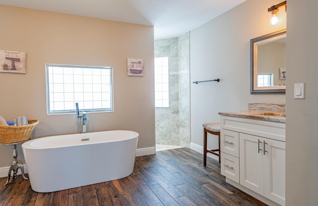 bathroom with a walk in shower, a soaking tub, vanity, wood finished floors, and baseboards