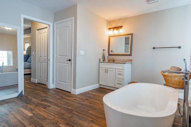 full bath featuring a freestanding bath, connected bathroom, vanity, and wood finished floors