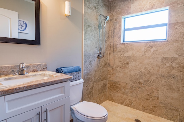 bathroom with a tile shower, vanity, and toilet
