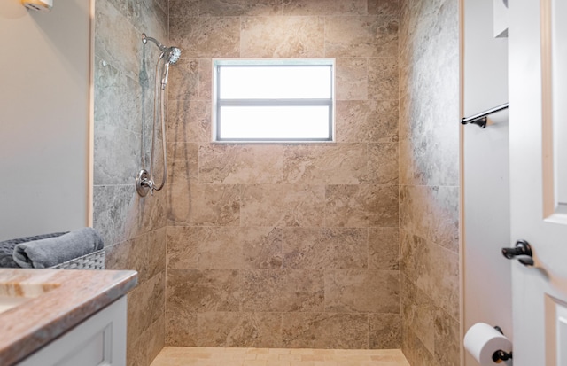 full bath featuring a tile shower and vanity