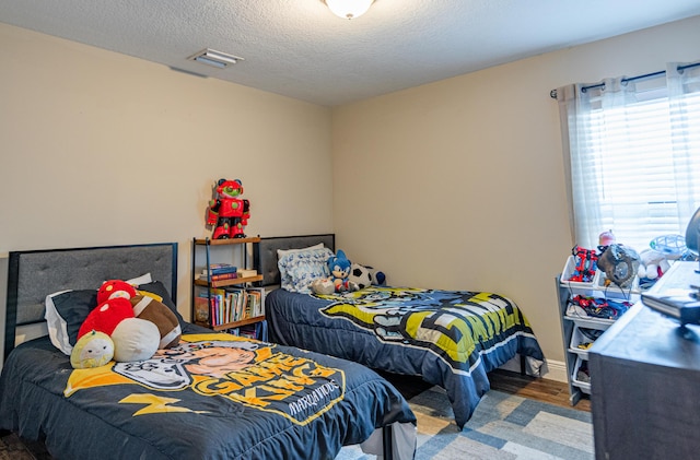 bedroom featuring a textured ceiling, wood finished floors, and visible vents