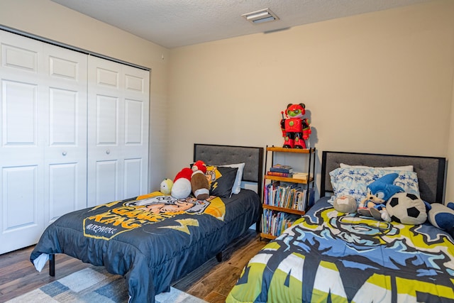 bedroom with visible vents, a closet, wood finished floors, and a textured ceiling