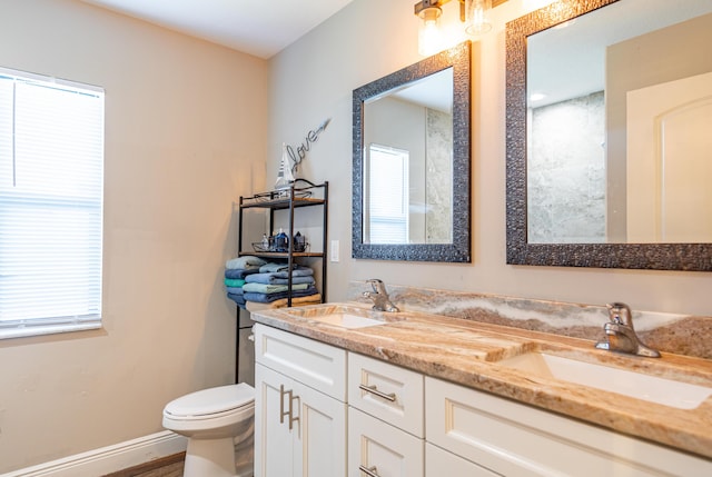 full bathroom featuring double vanity, baseboards, a sink, and toilet