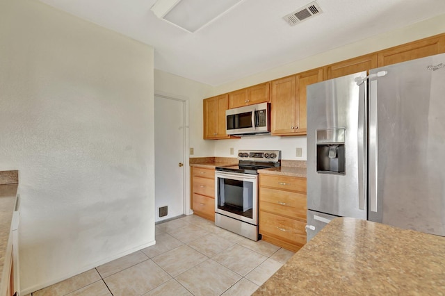 kitchen with stainless steel appliances, light countertops, visible vents, light tile patterned floors, and baseboards