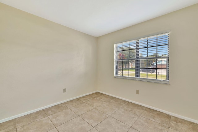 spare room with baseboards and light tile patterned floors