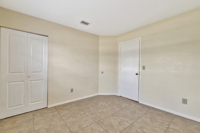 unfurnished bedroom with a closet, visible vents, baseboards, and light tile patterned floors
