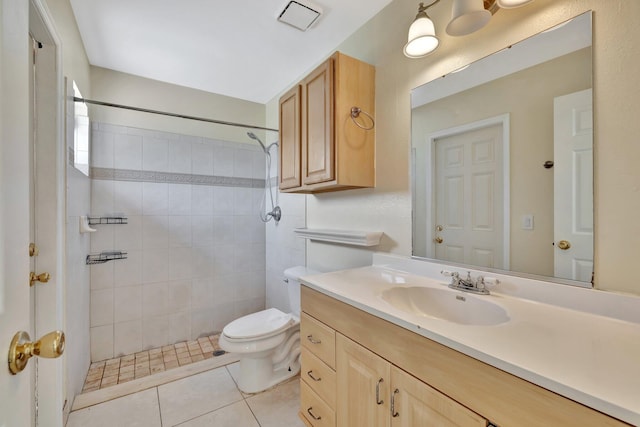 bathroom with tile patterned floors, a tile shower, vanity, and toilet