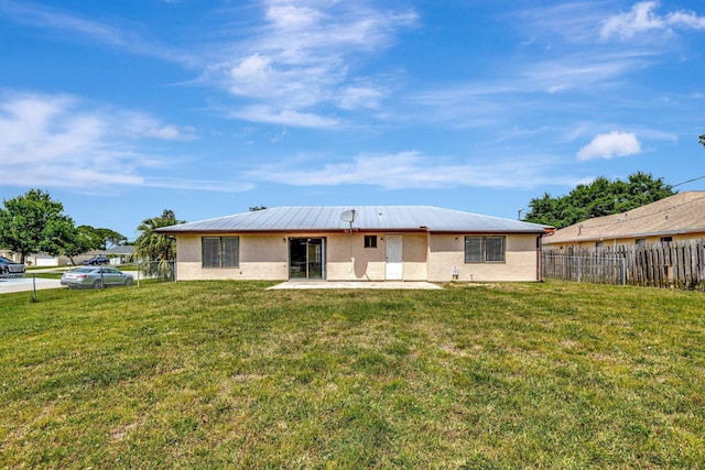 rear view of house with a yard, a patio area, stucco siding, and fence