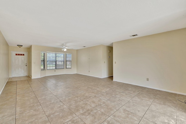 spare room featuring baseboards, visible vents, ceiling fan, and light tile patterned flooring