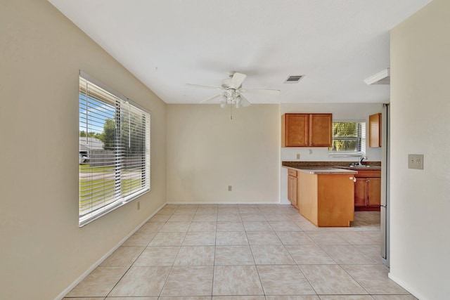 kitchen with visible vents, a ceiling fan, light tile patterned floors, a sink, and brown cabinetry