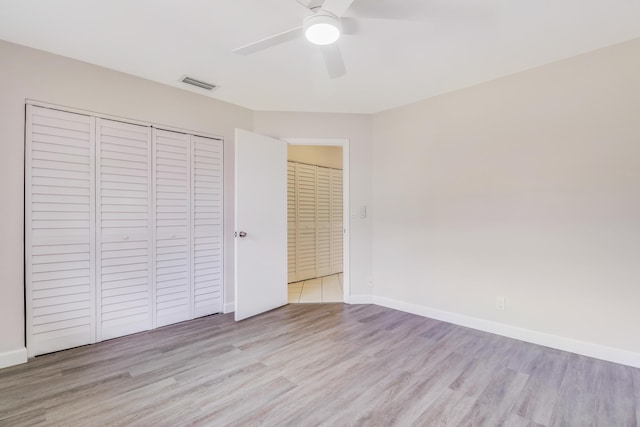 unfurnished bedroom with visible vents, baseboards, wood finished floors, and a closet