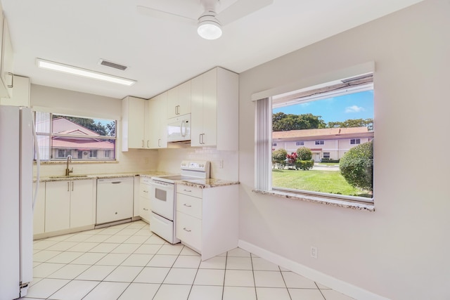 kitchen with a sink, white appliances, a ceiling fan, tasteful backsplash, and visible vents