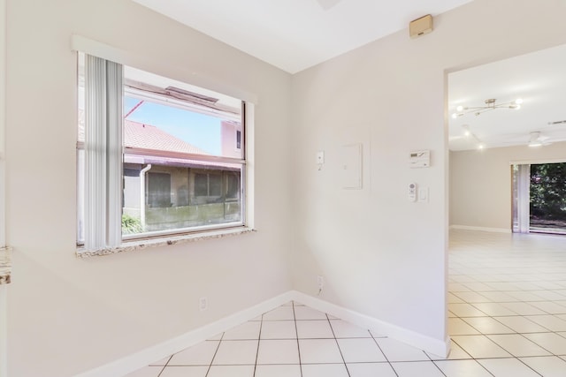 empty room featuring baseboards, light tile patterned flooring, and a healthy amount of sunlight