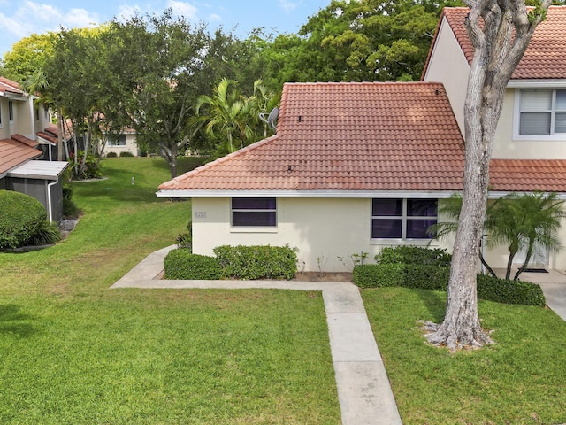 view of property exterior with a yard, stucco siding, and a tiled roof