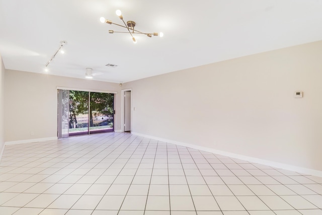 spare room featuring track lighting, baseboards, a notable chandelier, and visible vents