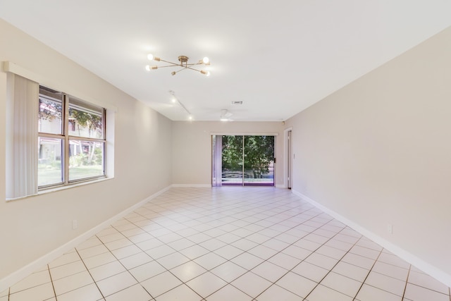 unfurnished room featuring baseboards, a chandelier, plenty of natural light, and light tile patterned floors