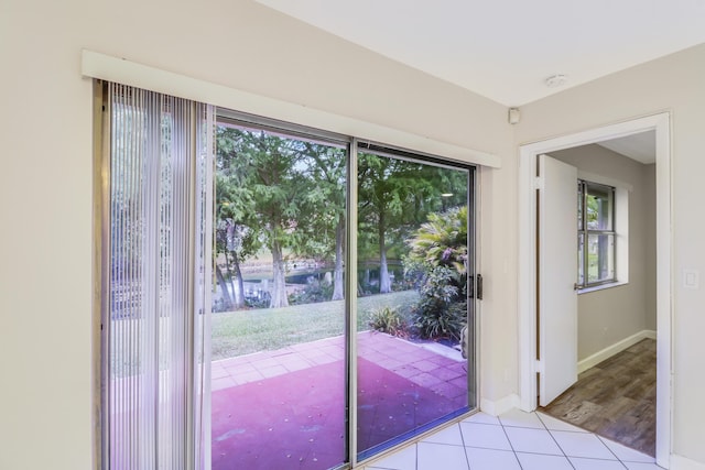 doorway with baseboards, plenty of natural light, and tile patterned flooring