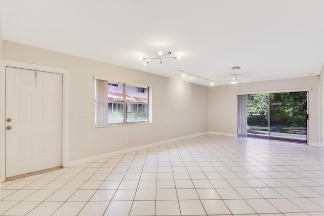 spare room with light tile patterned floors, rail lighting, visible vents, and baseboards