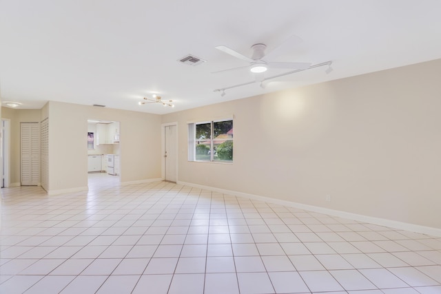 spare room with ceiling fan, visible vents, rail lighting, light tile patterned floors, and baseboards
