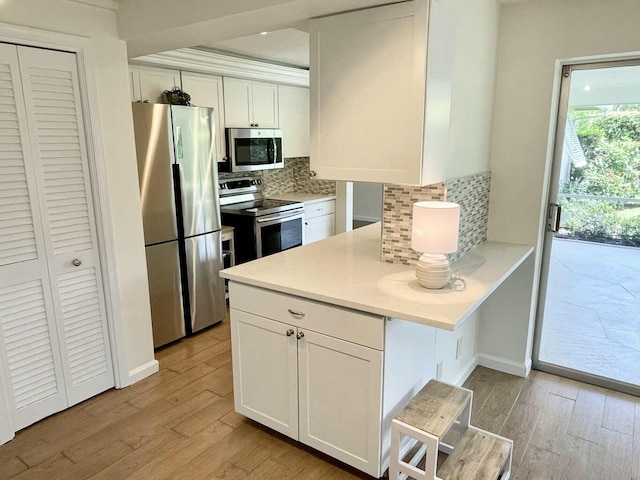 6401 NE 7th Ave, Boca Raton, FL 33487 - kitchen featuring appliances with stainless steel finishes, light wood finished floors, white cabinetry, and decorative backsplash