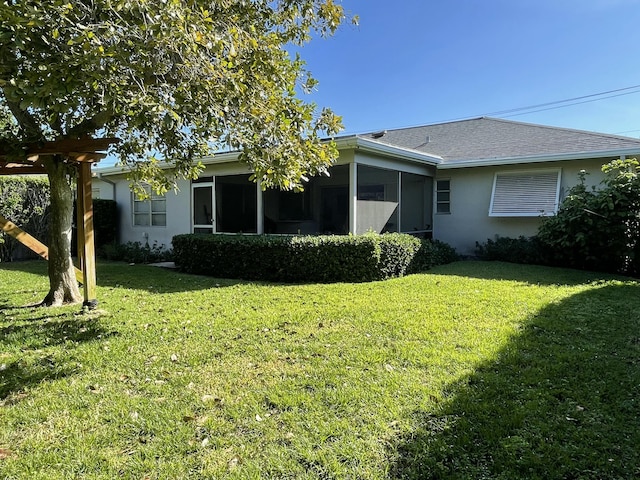 6401 NE 7th Ave, Boca Raton, FL 33487 - rear view of house with stucco siding, a lawn, a sunroom, and a shingled roof